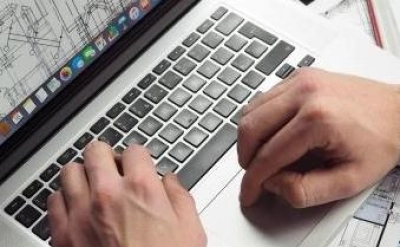 Bauplanung| Hände Schrieben auf einer Laptop Tastatur, auf dem Bildschirm ist ein Bauplan